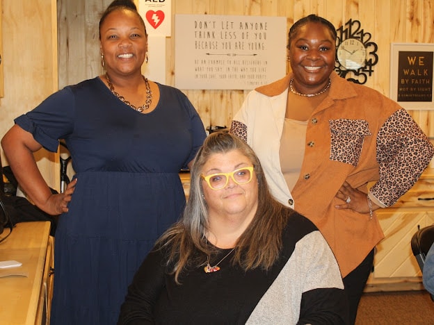 2025 Becoming Project — three women smiling together indoors